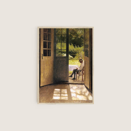 Framed artwork of a man sitting on a chair by an open door, looking out into a garden.