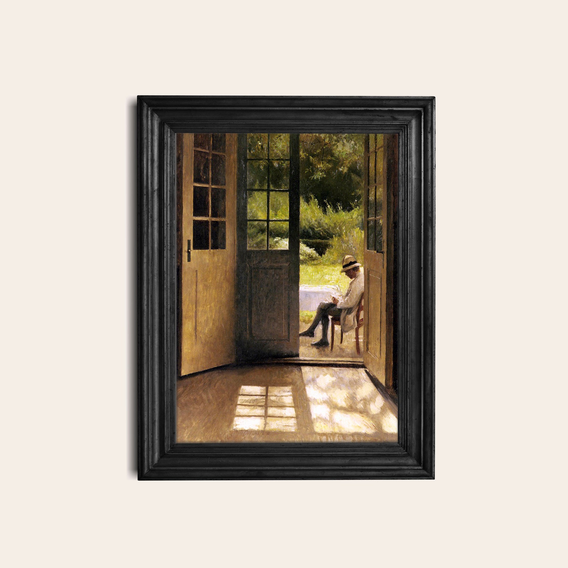 Framed artwork of a man sitting on a chair in a garden in a black frame hung on a light wall