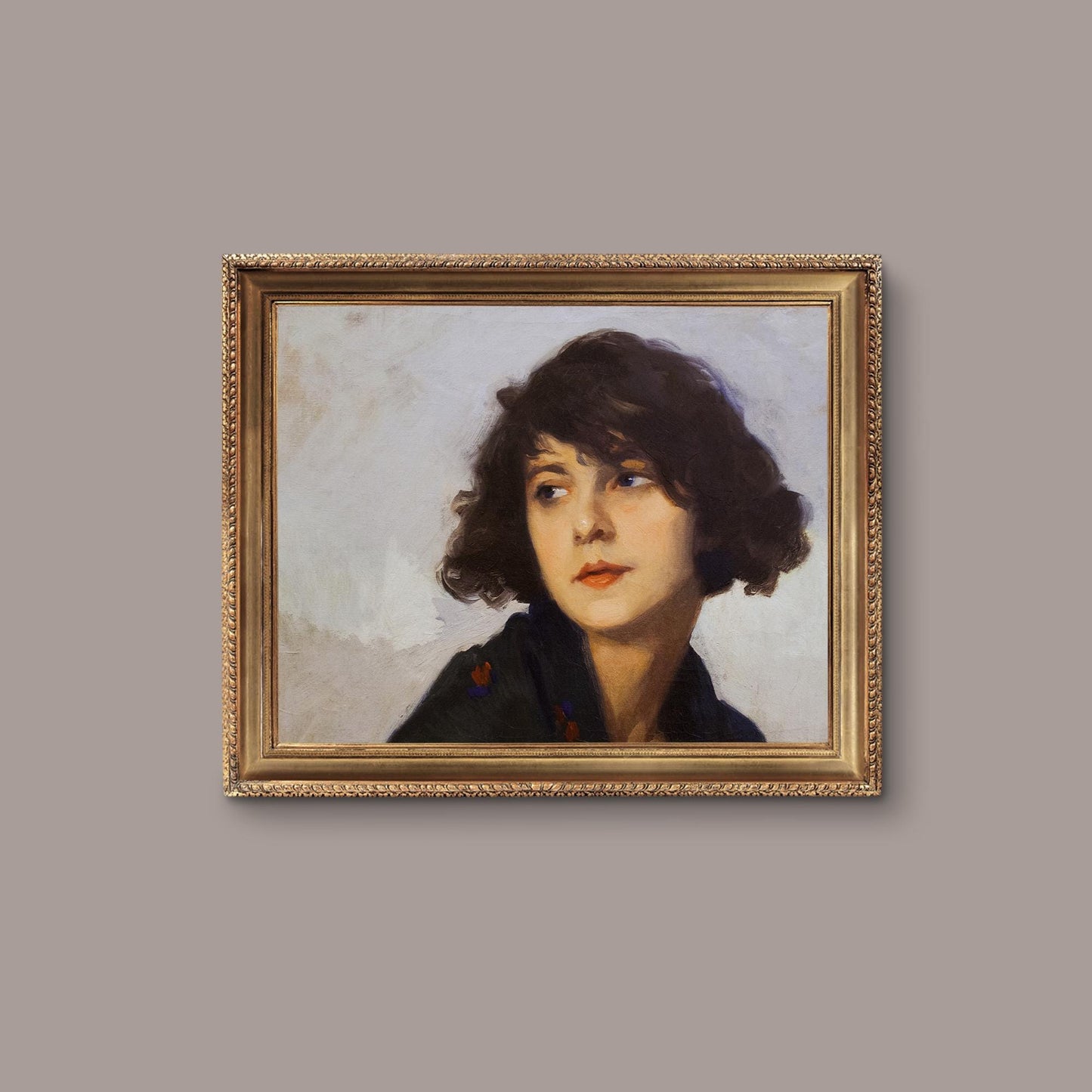 Framed portrait of a woman with a gold frame on a beige wall