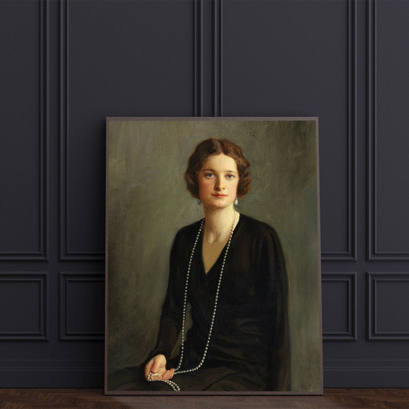 A fine art print of a beautiful portrait from the Art Deco period. The print is displayed resting against a dark panelled wall.