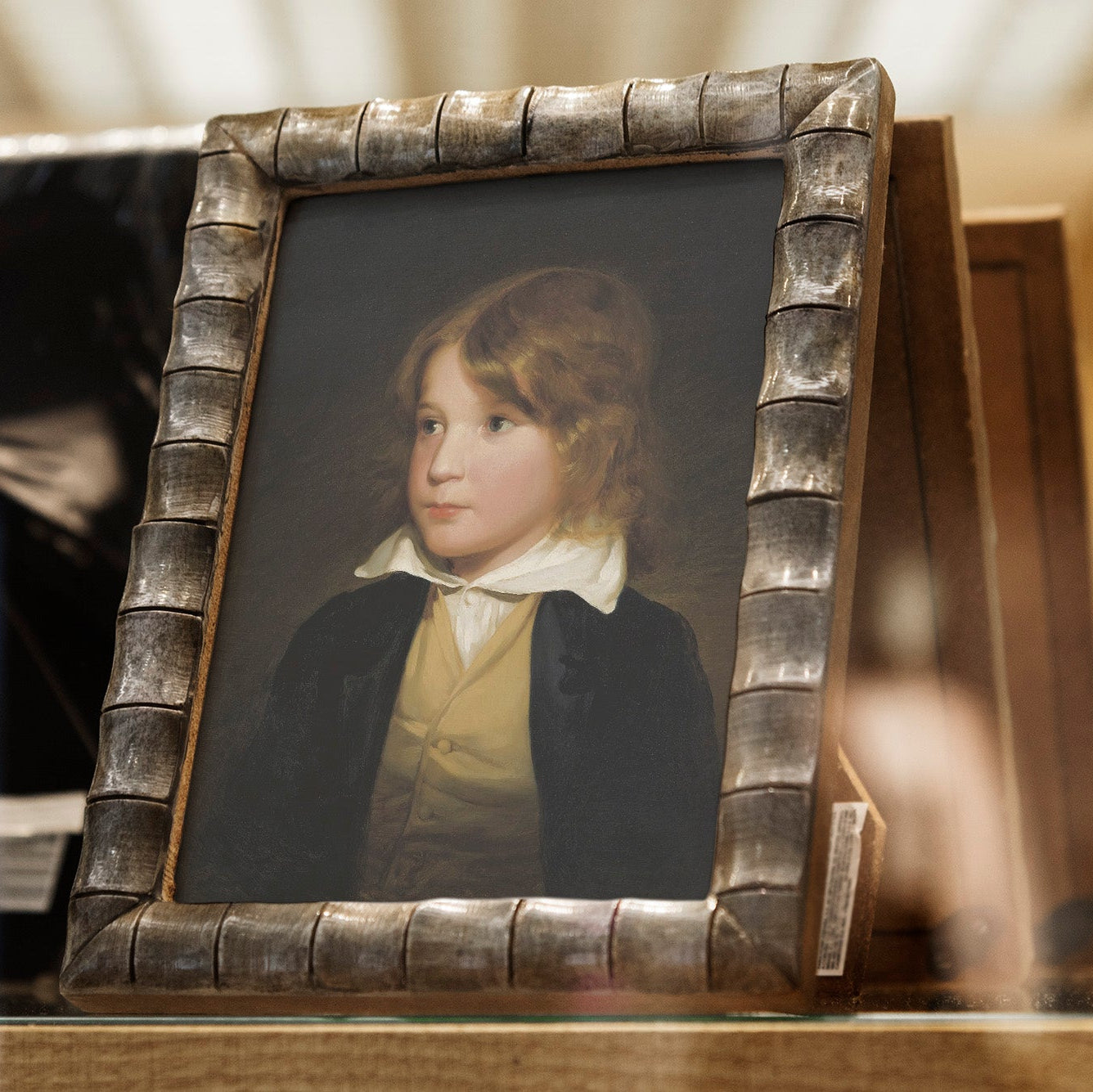 Small portrait of a young boy in a decorative frame on a wooden surface.