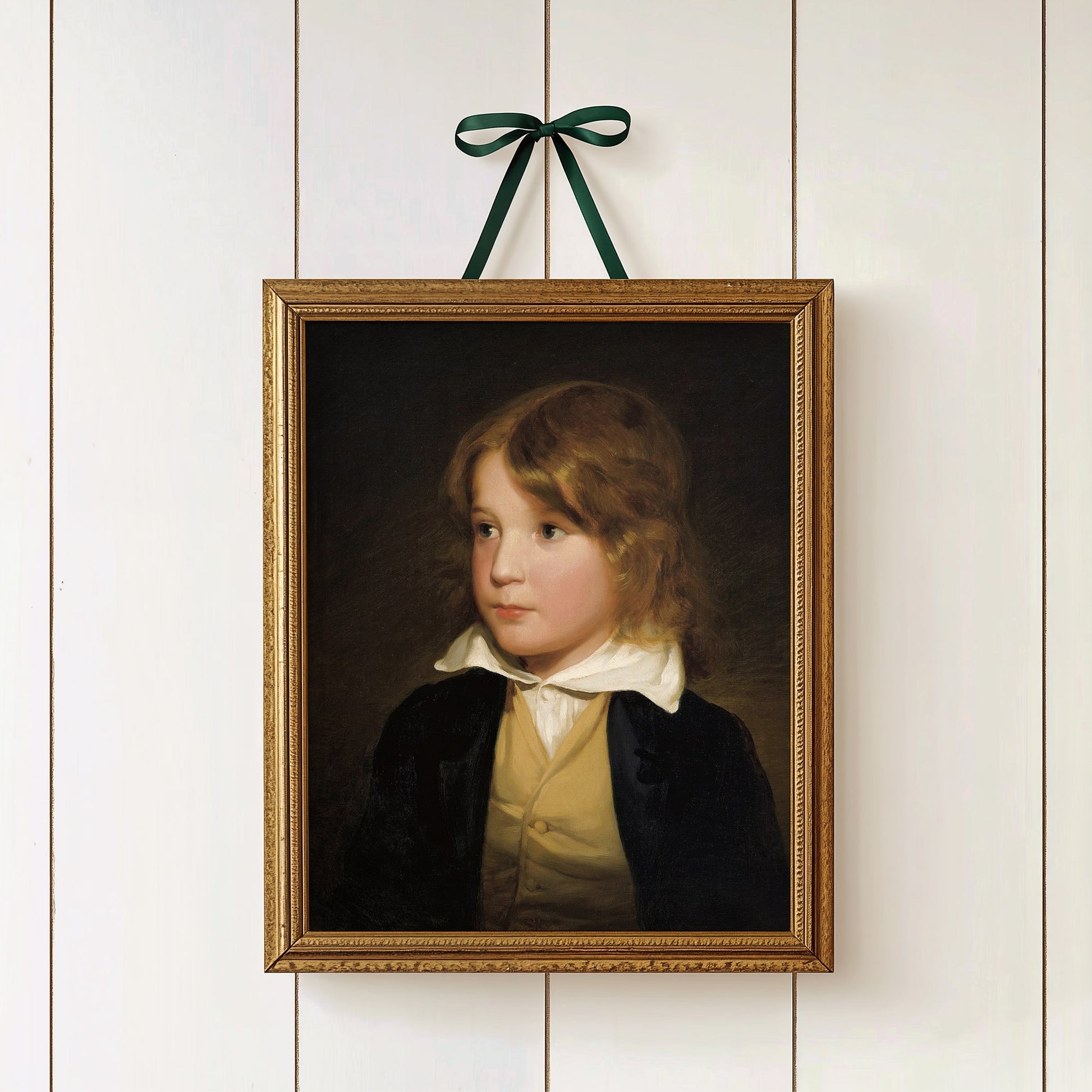 Framed portrait of a young boy on a white paneled wall with a green ribbon.