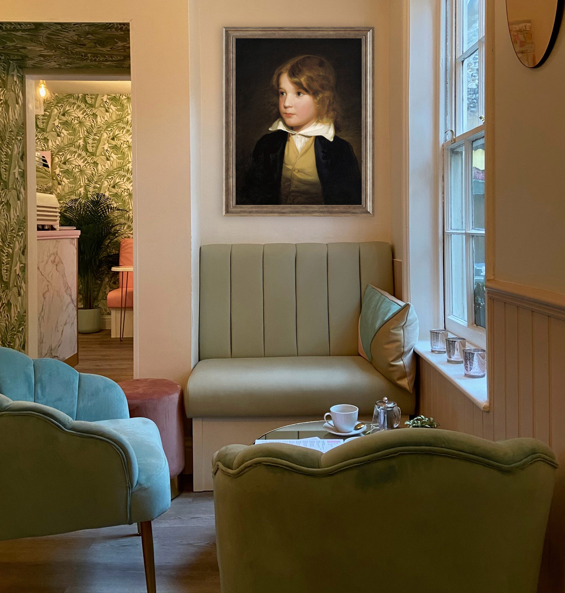 Living room with a portrait of a young boy on the wall, a green sofa, and a window.