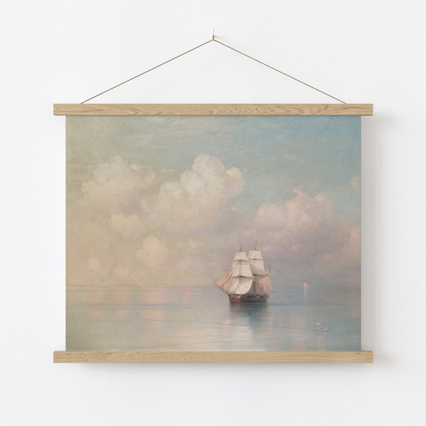 Framed artwork of a ship on water with clouds, hanging on a white wall.