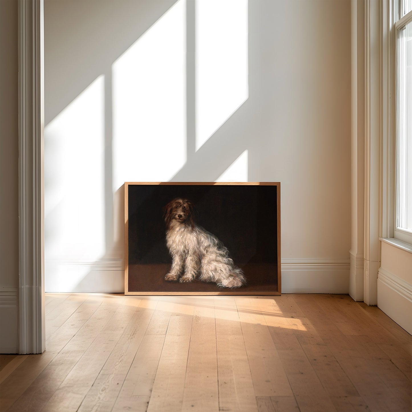Framed artwork of a terrier dog painted on a dark background in a room with wooden flooring and light streaming in through the window.