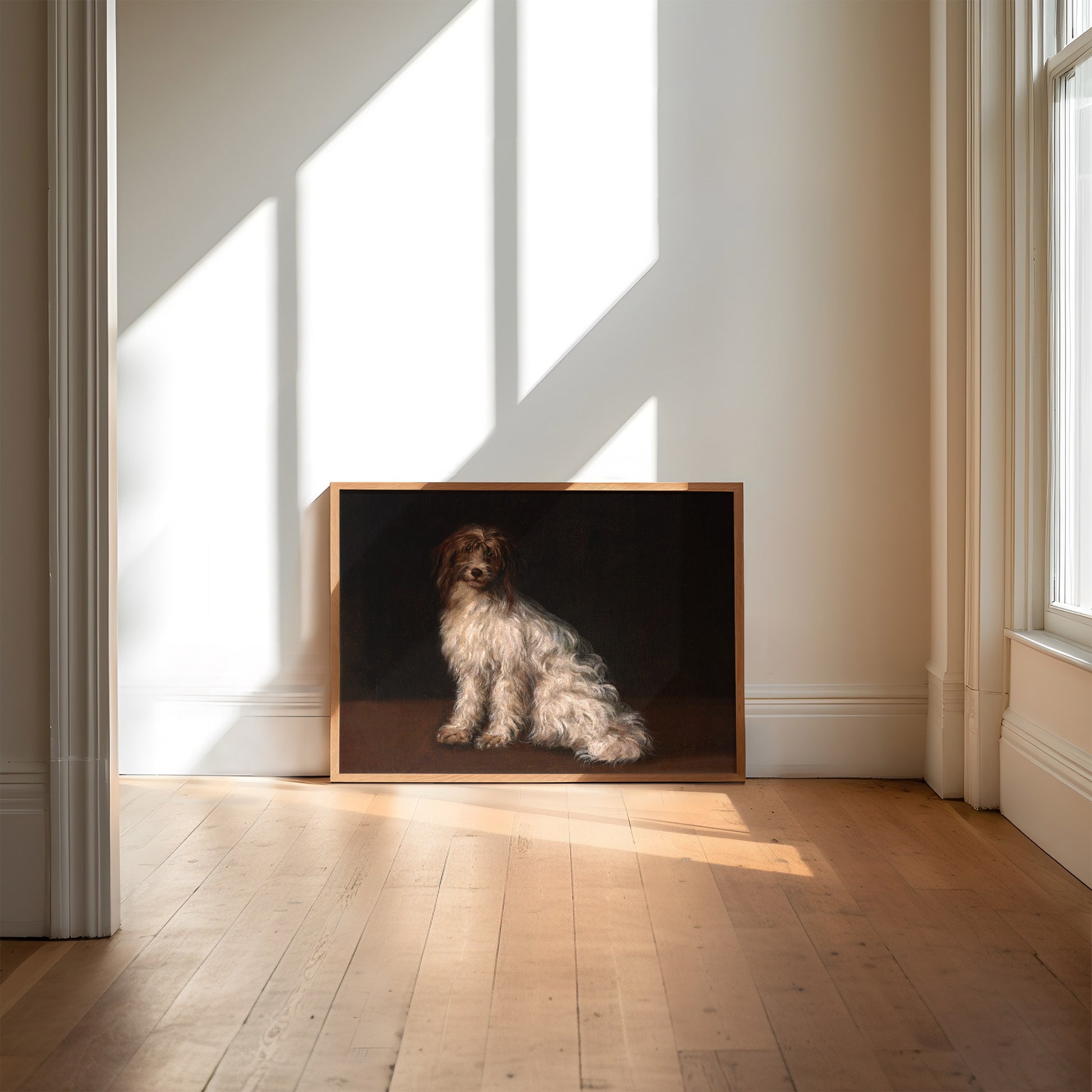 Framed artwork of a terrier dog painted on a dark background in a room with wooden flooring and light streaming in through the window.