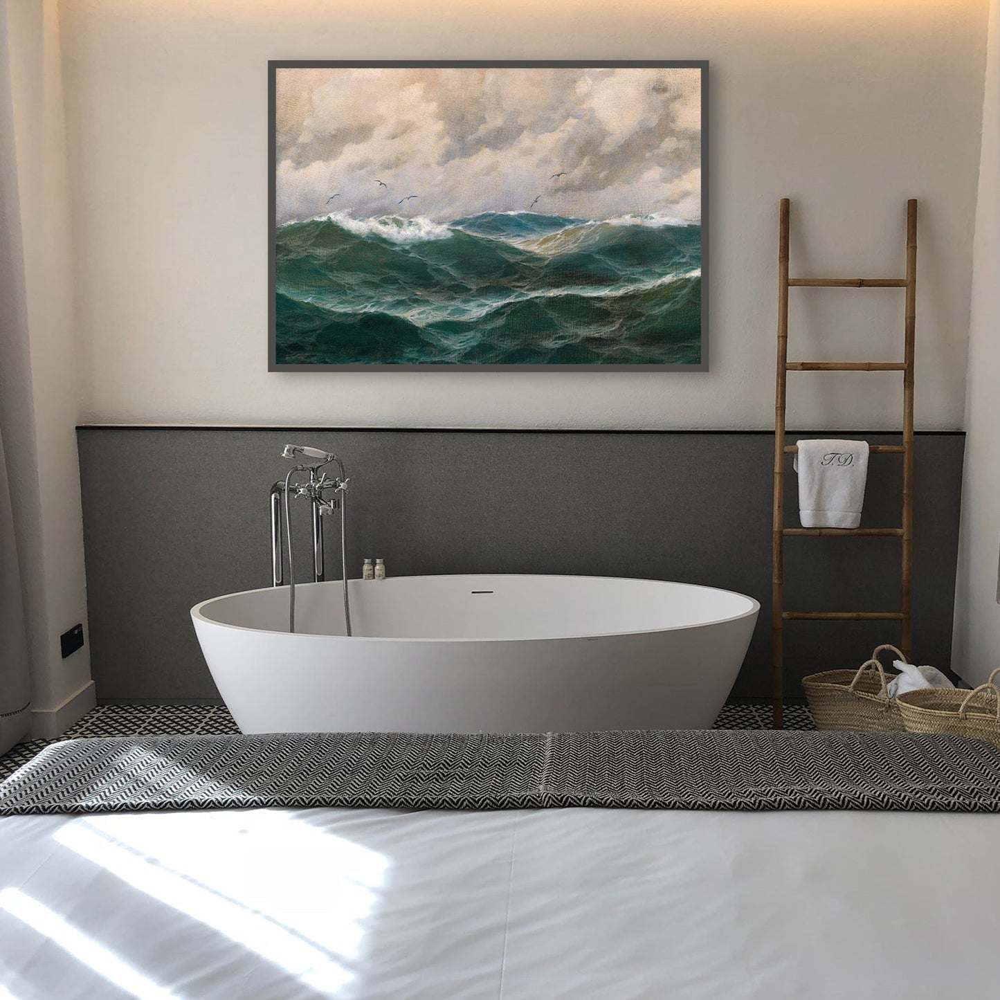 Modern bathroom with a freestanding bathtub, ladder, and framed fine art print of a seascape with turbulent seas and dramatic sky.