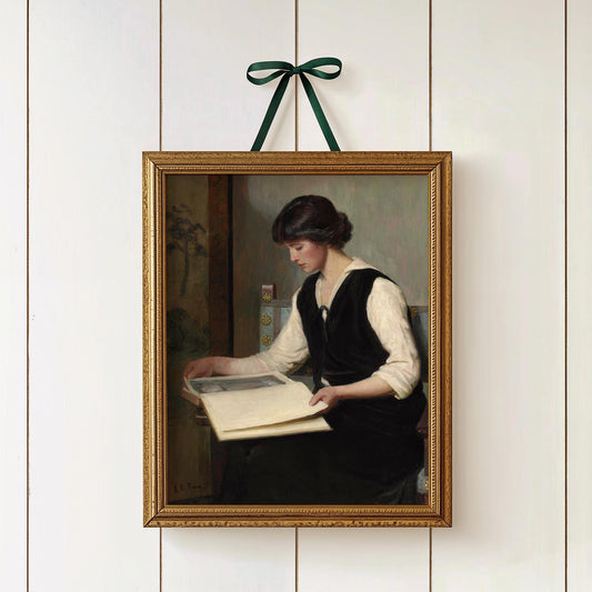 Framed print of a woman reading a book on a white wall with a green ribbon.