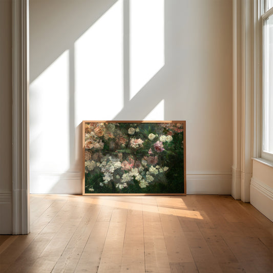 A framed art print of a rose garden in full bloom, resting on a wooden floor with light flooding through the window.