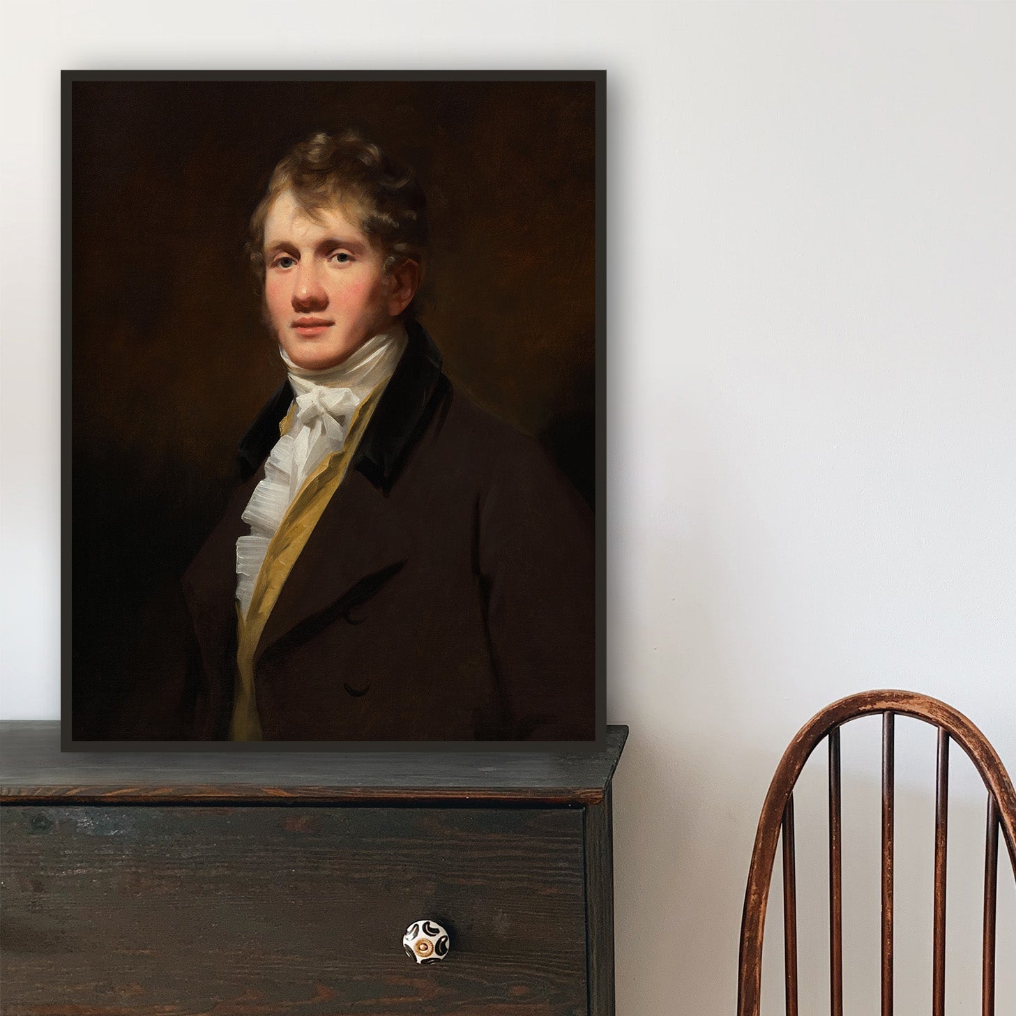 Wooden chair and dark wooden dresser with portrait on a light gray wall.