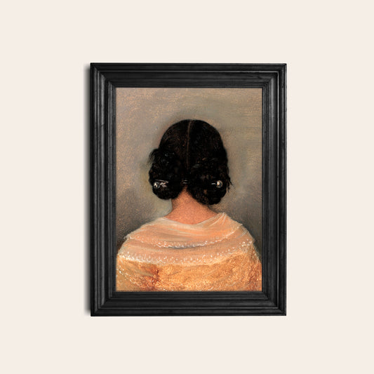 Framed print of a woman from behind with braided hair in a black picture frame hung on a white wall.