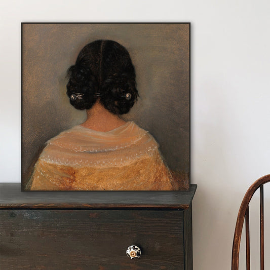 Framed print of a woman's back resting on a wooden dresser.