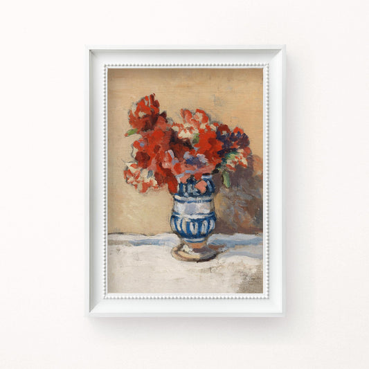 A fine art print of a still-life oil painting of red flowers in a blue and white striped vase. The print is displayed in a white picture frame.