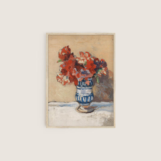 A fine art print of a still-life of red flowers in a charming blue and white striped vase. The print is displayed in a thin wooden picture frame.