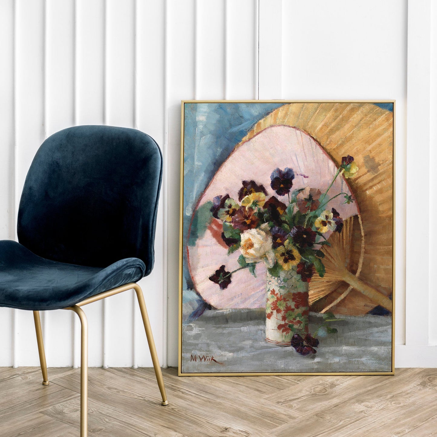Framed artwork of a floral arrangement leaning against a wall next to a dark blue chair.
