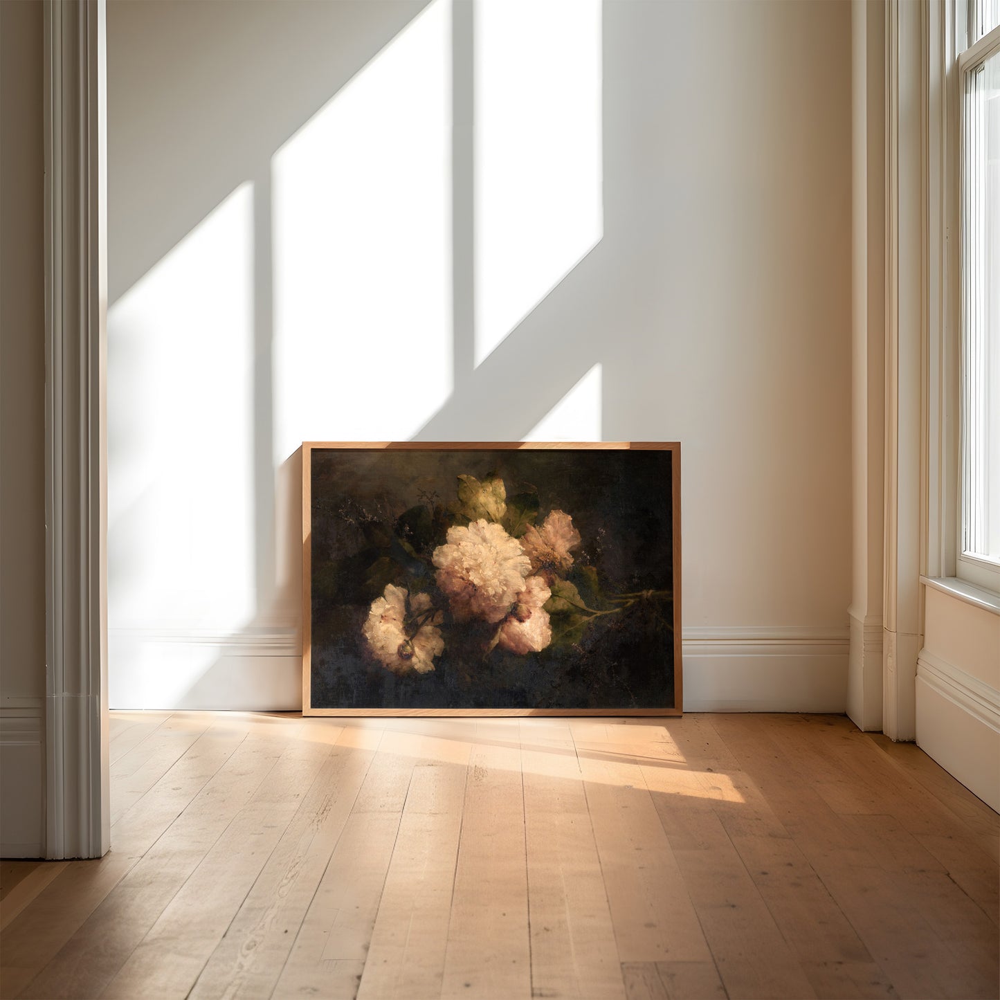 Framed artwork resting against a wall in a room with sunlight streaming through windows