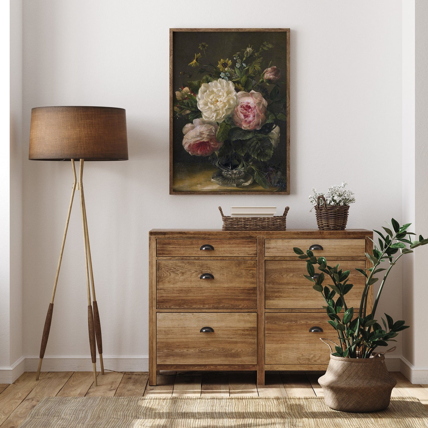 Wooden dresser with a lamp, plant, and floral print in a room.