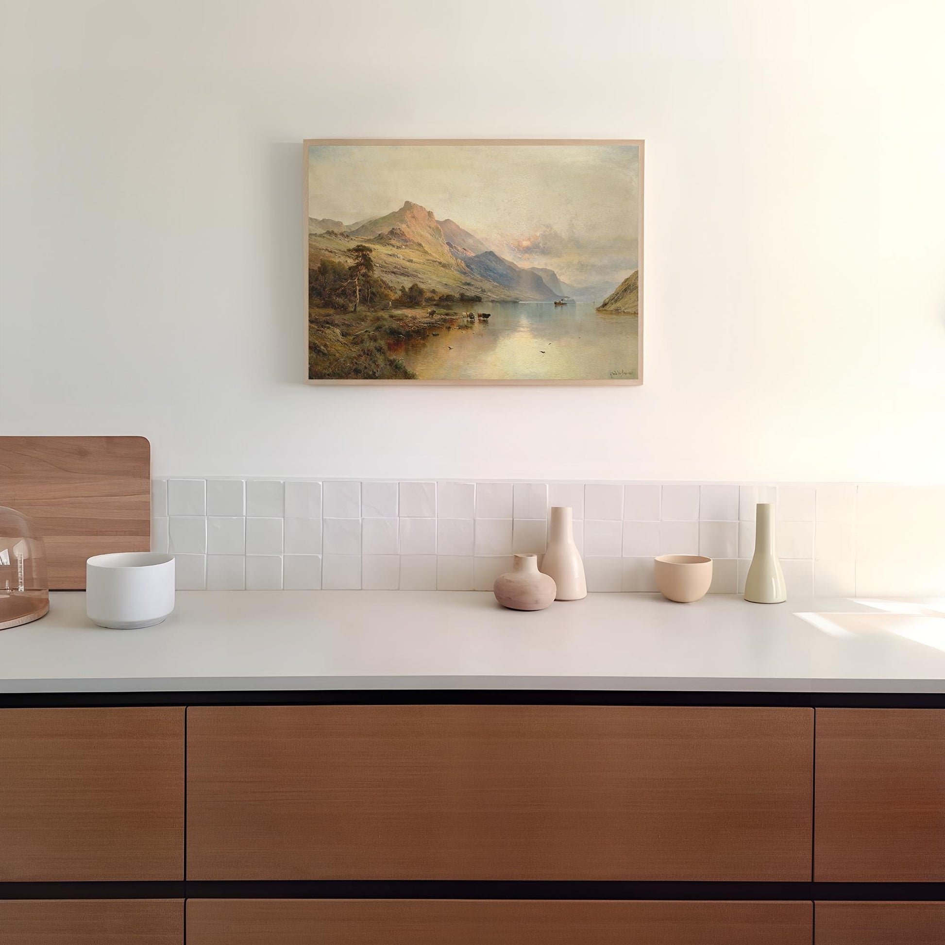 Modern kitchen with wooden cabinets, white countertop, and a landscape print on the wall.