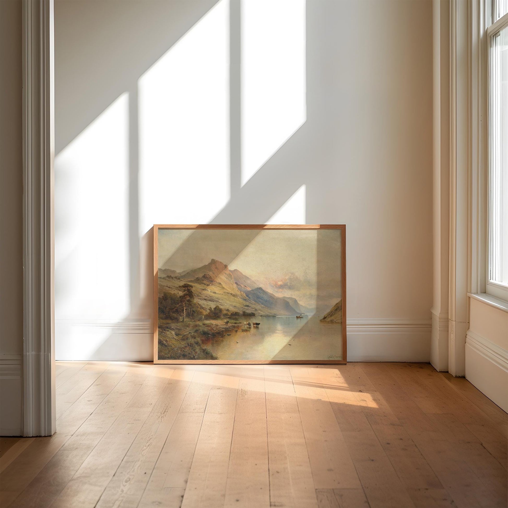 Framed landscape print on a wall in a bright room with sunlight streaming through windows.