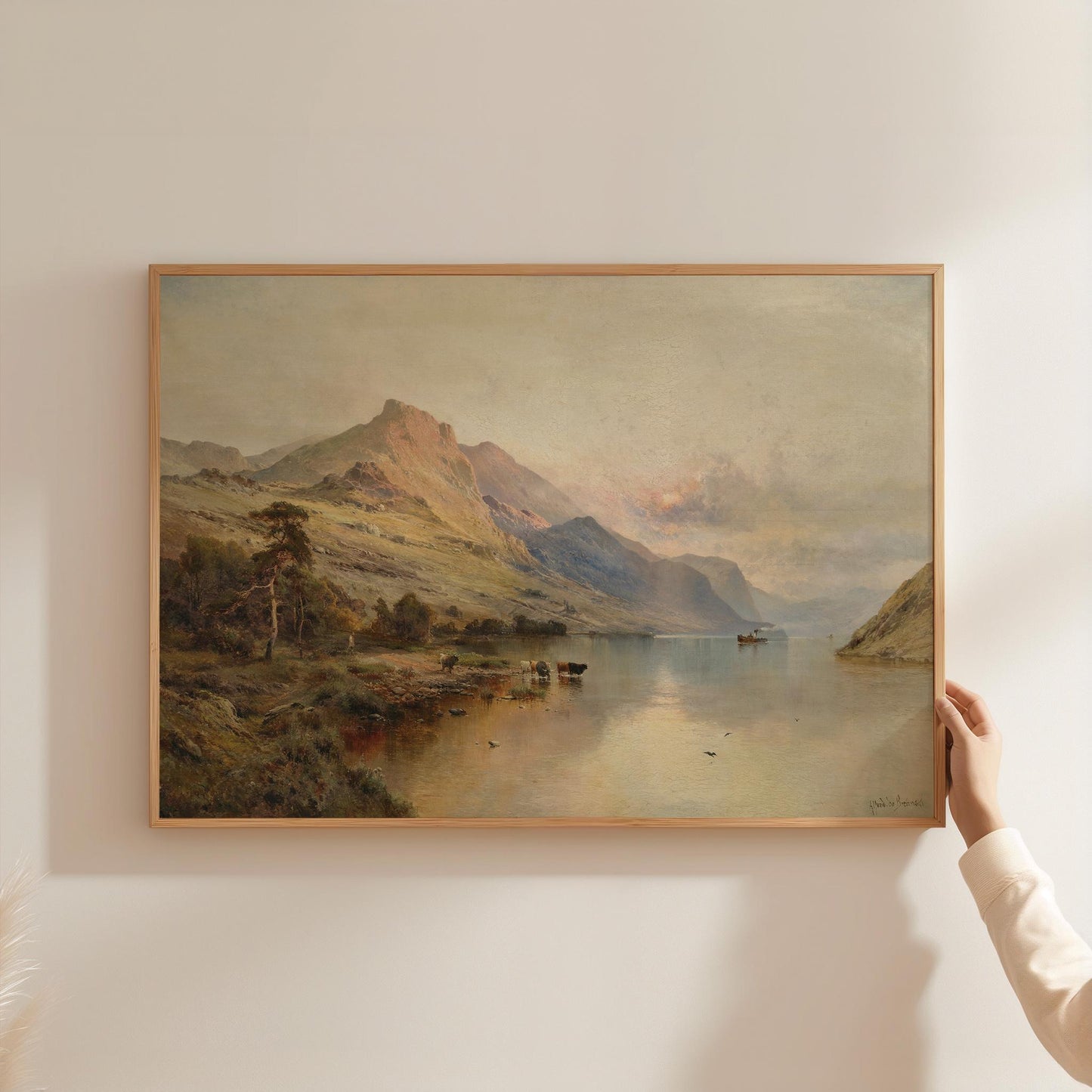Framed landscape print of a lake and mountains on a wall.