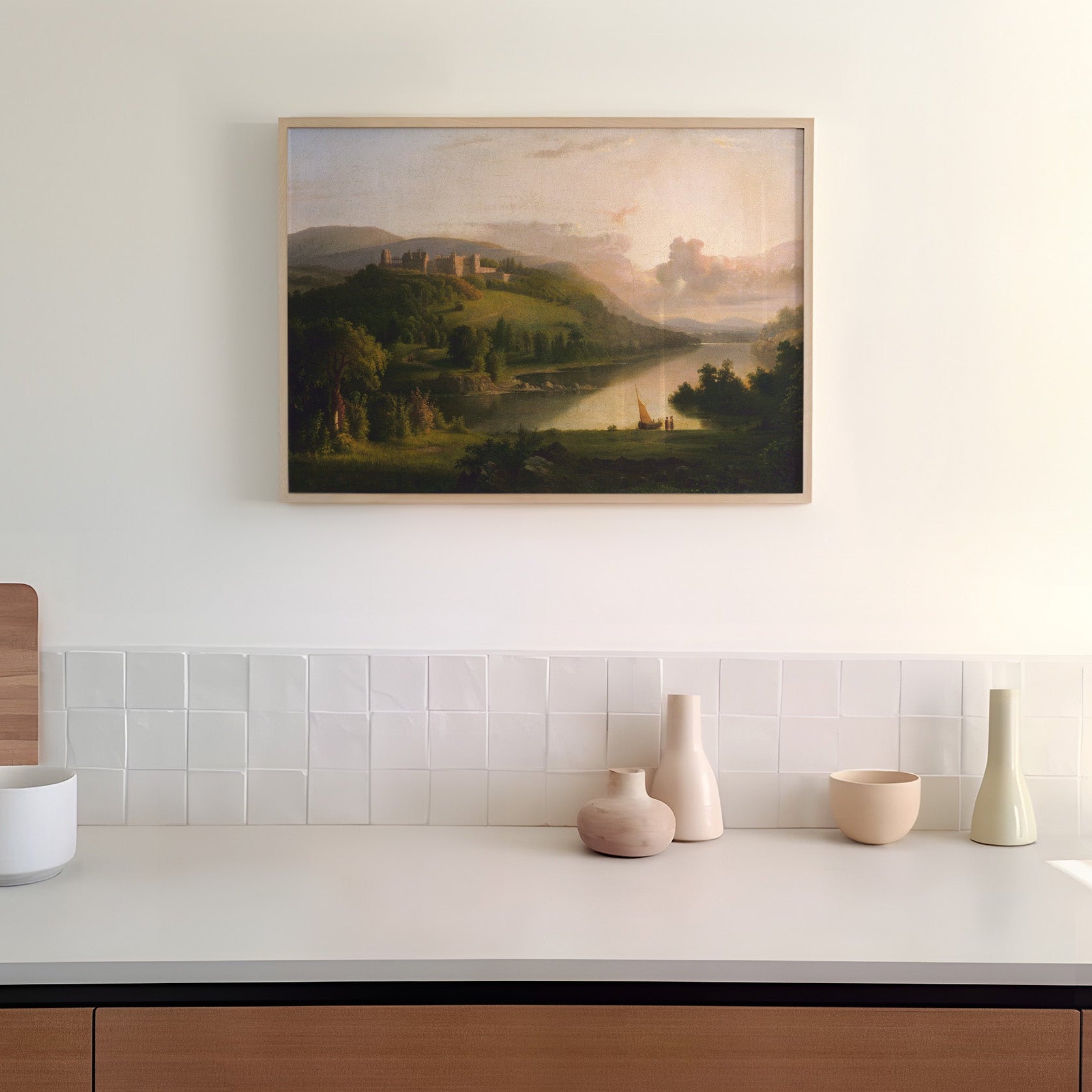 Framed landscape painting above a kitchen counter with decorative vases.