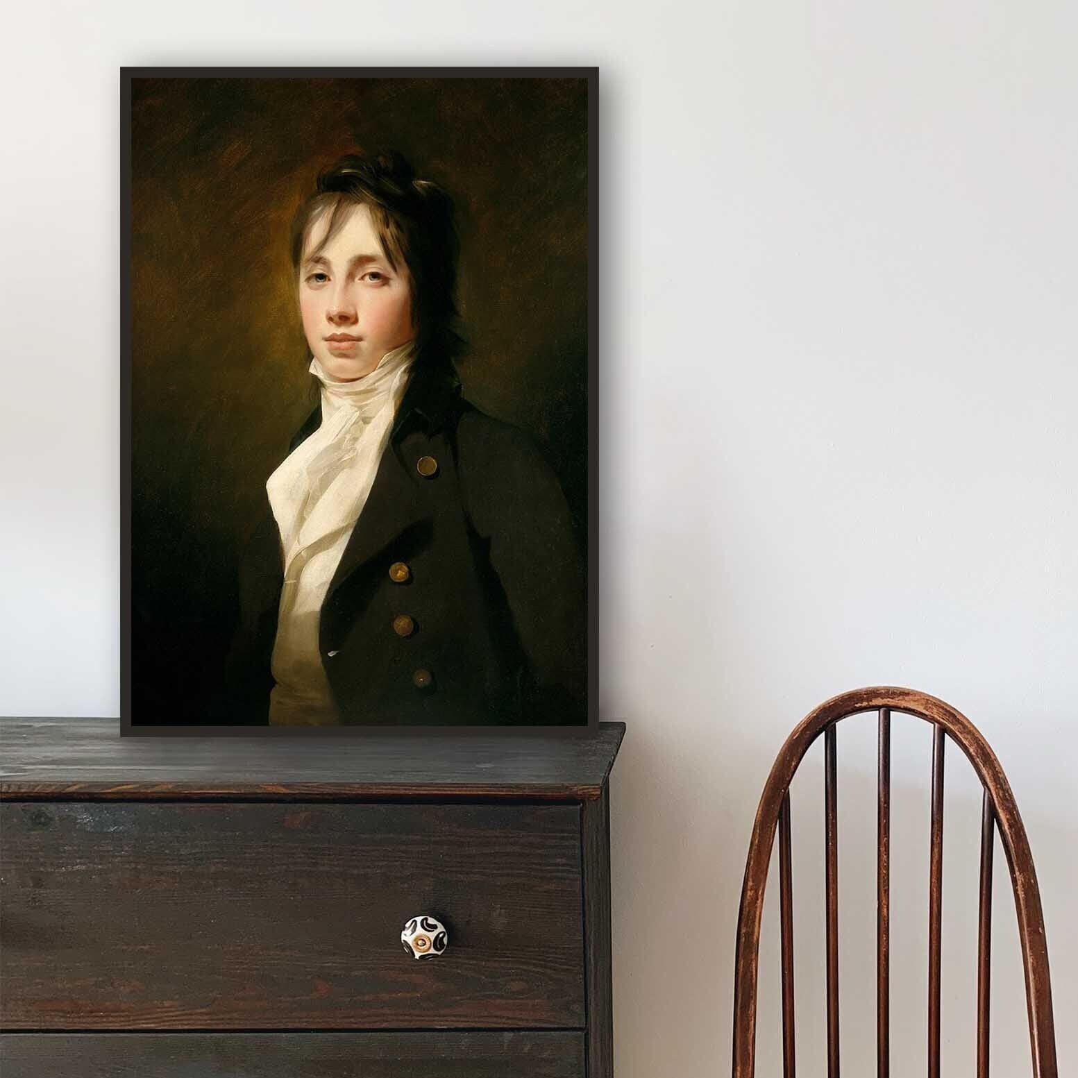 Framed male portrait print on a wooden dresser with a chair in the background
