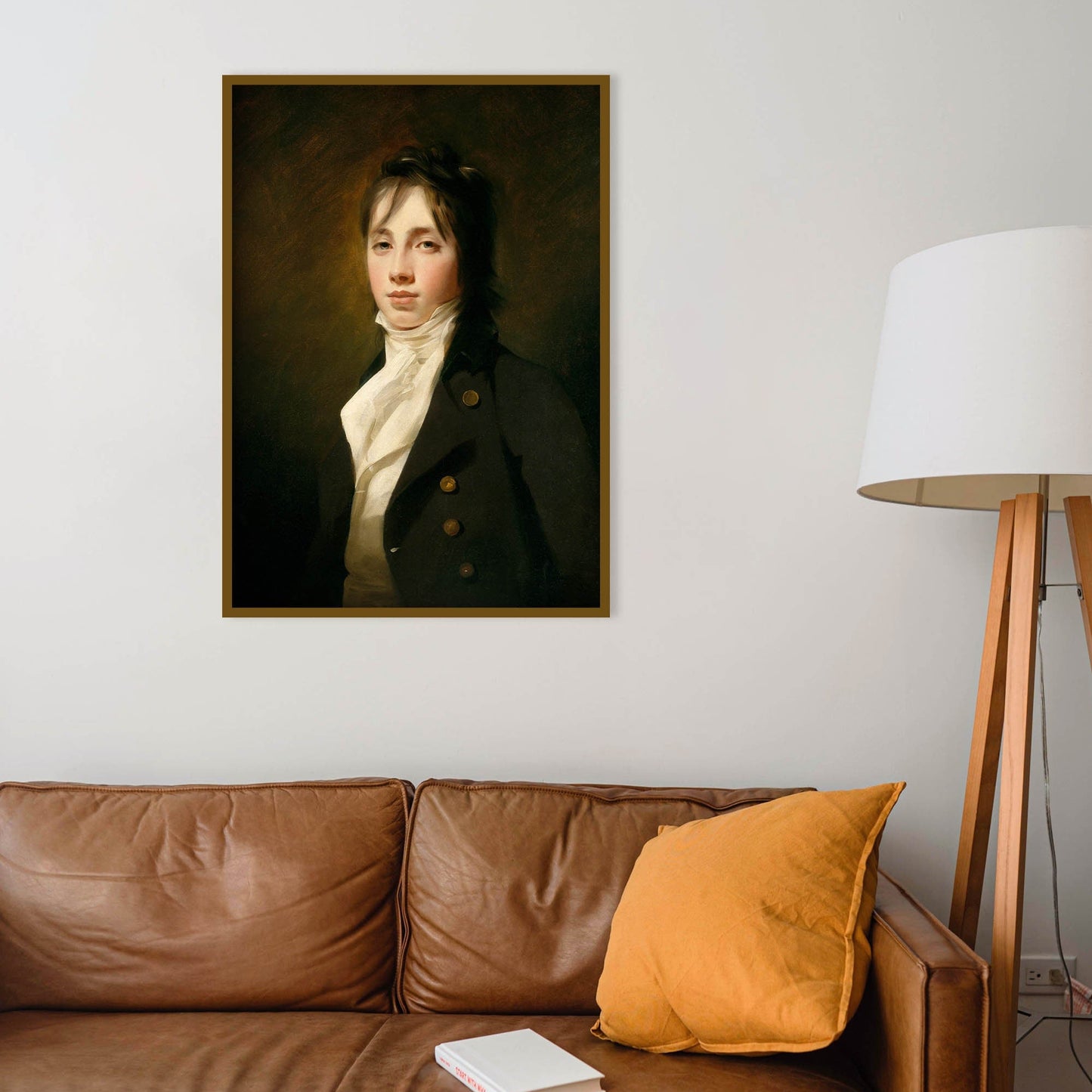 Portrait of a man on the wall above a brown leather sofa with a lamp to the right.