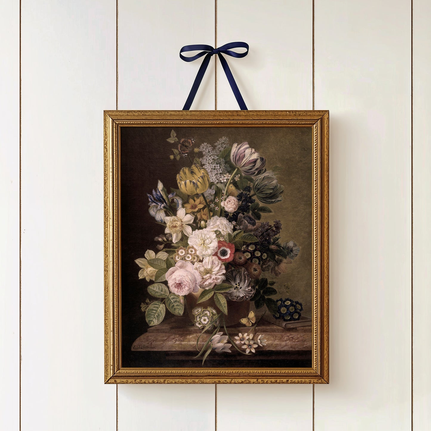 Framed floral print with a blue ribbon on a white paneled wall